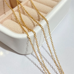 Close-up of elegant gold plated link chain draped over a white velvet jewelry box