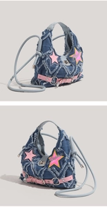 Detail view of denim crossbody bag with pink star patches and fringe raw edges