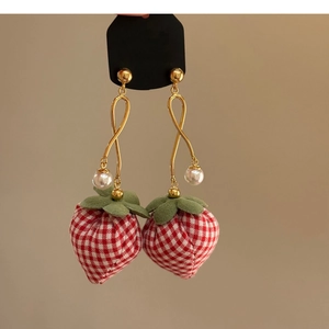 Macro shot of handmade strawberry earrings with red checkered fabric and white pearl accents