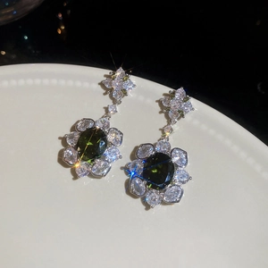Macro detail of silver floral drop earrings with emerald green oval zircon and crystals