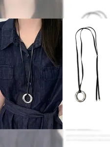 Close-up of minimalist resin ring pendant with black adjustable cord on denim fabric