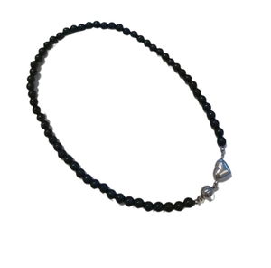 Elegant beaded necklace with black pearls and a metallic heart magnetic clasp on white backdrop