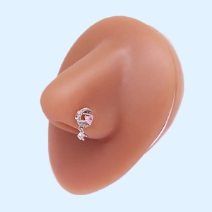 L-shaped nose stud with silver moon and pink heart gemstone on skin-tone silicone model