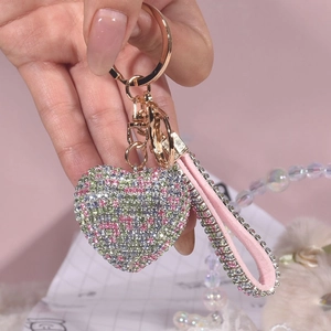 Makro-Detail des bunten Herz-Schlüsselanhängers mit rosa Lederband und Glitzersteinen