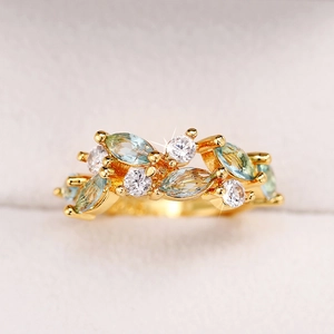 Macro detail of leaf-shaped marquise emerald and round zircon gold floral ring