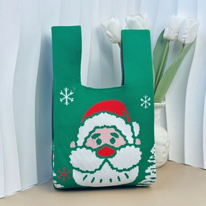 Detail of green knitted Christmas tote bag with Santa Claus and snowflake pattern texture
