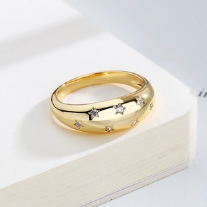 Macro detail of gold dome ring with star engravings and cubic zirconia on a notebook