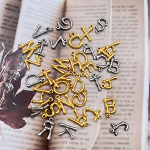 Anhänger mit 18K Gold- und Silberbuchstaben auf Vintage-Buchseiten im Bambus-Stil