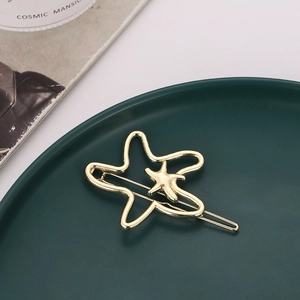 Hollow gold starfish hair clip with layered 3D design on a green ceramic plate