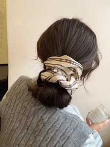 Detail of a large cream striped scrunchie on a low bun hairstyle with autumn knitwear