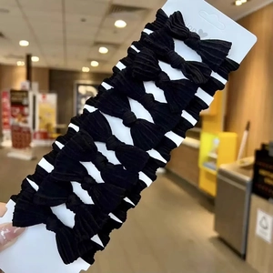 Close-up of ten black bow elastic hair ties displayed on a white cardboard retail card