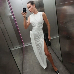 Detail van de witte mouwloze maxi-jurk met geplooid ontwerp en hoge zijsplit