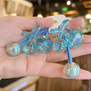 Close-up of blue cherry-shaped acrylic hair ties with faceted charms and elastic bands