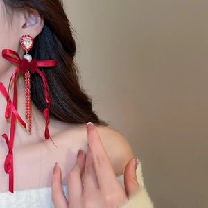 Gros plan de boucles d'oreilles nœud en velours rouge avec glands et perles