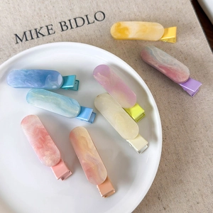 Pastel marble resin hair clips set with glitter finish on white ceramic plate