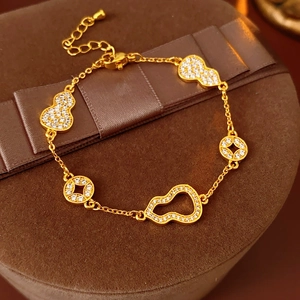 Macro shot of 24k gold plated gourd and coin charms on a luxury jewelry box
