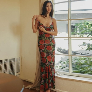 Détail d'une robe longue à fleurs avec motifs de roses rouges et feuilles vertes sur noir