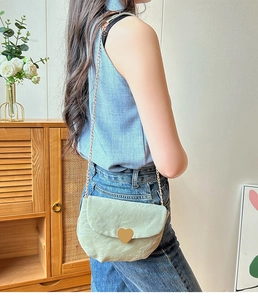 Détail du sac selle vert menthe avec grande boucle cœur dorée et bandoulière chaîne