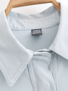 Detail of light blue twill fabric texture and collar on a wooden hanger shirt