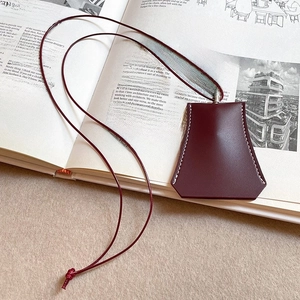 Close-up of burgundy leather bell key charm with white stitching on design magazine