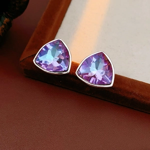 Gros plan de boucles d'oreilles triangulaires en cristal violet sur cuir marron