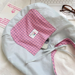 Detail of light blue canvas tote with pink plaid pocket on white fabric background