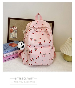Detailed macro shot of the pink corduroy material and embroidered cherry patterns on backpack