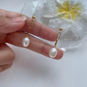 Elegant gold chain earrings with white drop pearls on a display card showcase