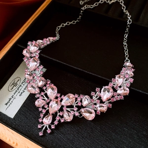 Detailed view of pink teardrop crystal necklace with silver setting on black velvet