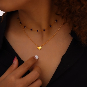 Double-layered gold necklace with blue beads and a 3D heart pendant worn by a model