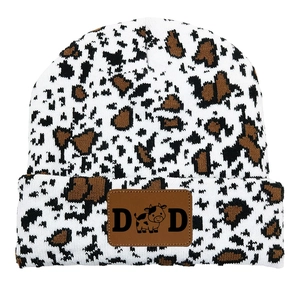 Detailed view of the cow print knit hat featuring a vintage leather patch with DAD text