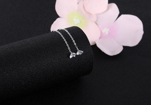 Detailed view of silver tassel earrings with transparent zircon hanging by pink flowers