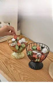 Detailed view of metal wire coffee pod holder baskets in gold and black finishes