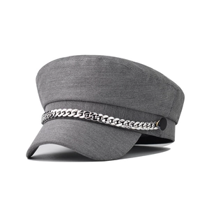 Macro detail of a grey beret hat with a silver metal chain and fabric texture