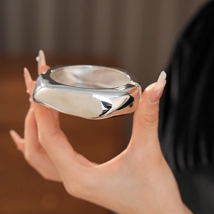 Close-up of wide irregular silver cuff bracelet showing thick metallic curved surface