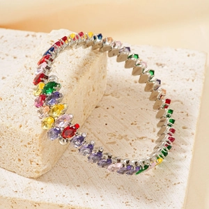 Silver open bangle with colorful oval-cut gemstones on a neutral stone display