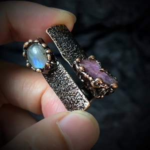 Macro shot of vintage bronze wide ring with natural labradorite and red raw gemstones