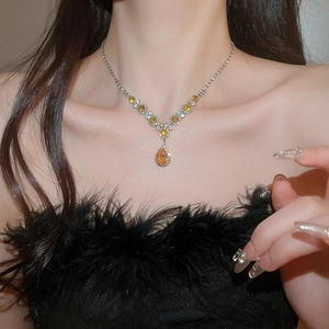 Close-up of a pear-cut yellow gemstone pendant necklace with zircon accents on a model