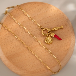Collier doré avec pendentifs poisson, coquillage et piment sur socle en bois