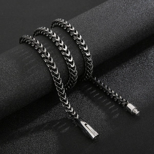 Detail of a black steel wheat chain necklace with professional textured finish