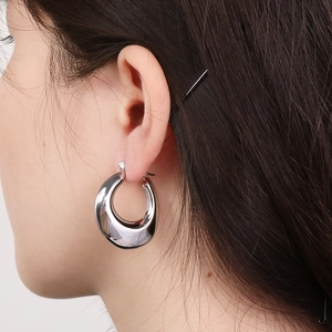Close-up of polished silver U-shaped hoop earrings on a model showing sleek metal texture