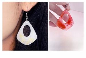 Close-up of geometric resin earrings in water drop shape with glitter and golden accents
