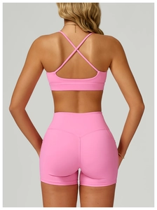Pink high-elasticity yoga set with cross-back sports bra and high-waisted shorts detail