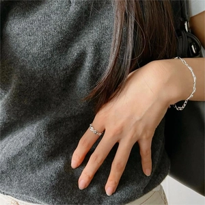 Detail of minimalist 925 sterling silver ring and bracelet set on a grey knit sleeve