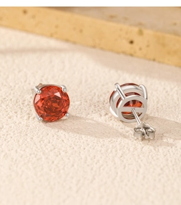 Macro di orecchini a perno con pietre rosse tonde e montatura a quattro griffe in argento