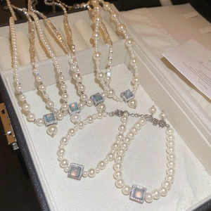 Close-up of pearl necklace with square blue gemstone pendant on jewelry box
