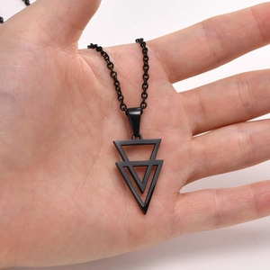 Detail of a men's black geometric triangle pendant necklace held in hand