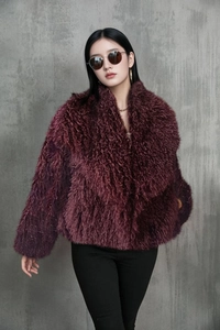 Detailed texture of fluffy dark purple faux fox fur on a stylish short cropped jacket
