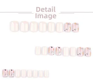 Detailed view of off-white press-on nails with pink floral patterns and gold foil flakes