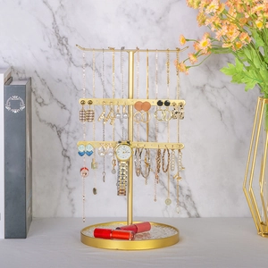 Three-tier golden metal jewelry organizer stand for necklaces and earrings on vanity desk